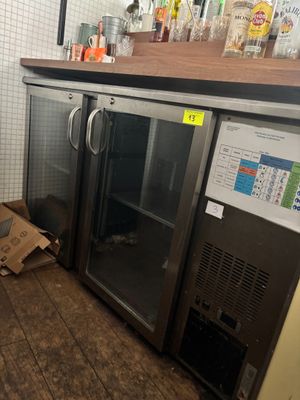 une boîte de pizza posée par terre à côté d'un réfrigérateur
