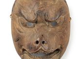 un vieux masque en bois sur fond blanc, avec un petit trou au milieu