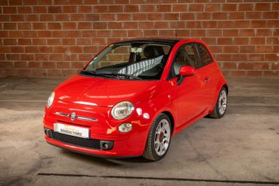 a small red car parked in front of a brick wall