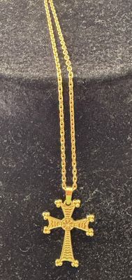 a gold necklace with a cross on it sitting on a black surface