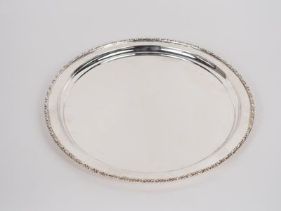 Grand plat rond en métal argenté, à décor d'une frise de feu…