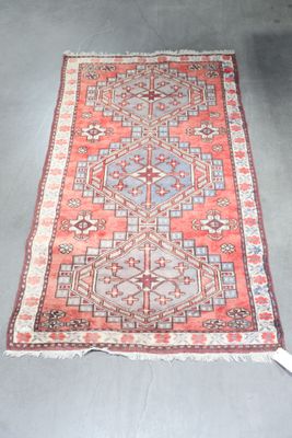 an old rug with a red and blue design on a grey floor