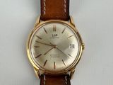 a close up of a watch on a white surface with a brown strap