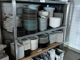 many plates and bowls stacked on a shelf in the kitchen