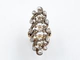un gros plan d'une bague ornée de perles et de diamants sur un fond blanc