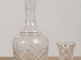 a glass bottle and a glass goblet sitting on a table