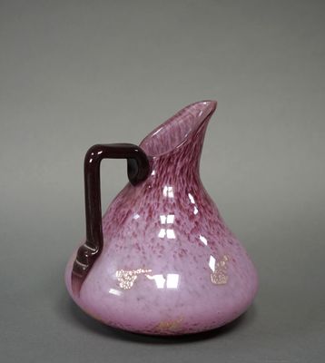 a purple vase with a brown handle on a gray surface
