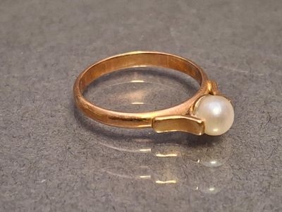 a gold ring with a pearl in it on a table