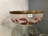 a glass bowl sitting on a glass table with a gold rim