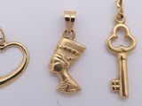 three gold pendants of different shapes and sizes with a heart and a key