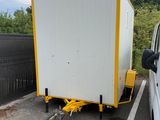 un camion blanc attelé à une remorque jaune dans un parking