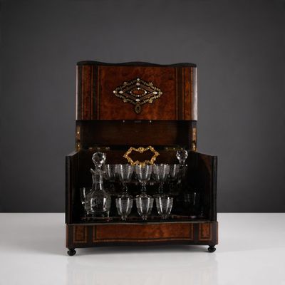 un ancien meuble à alcool en bois sur lequel sont posés des verres à vin