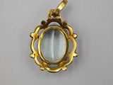 a close up of a gold plated pendant with a blue stone