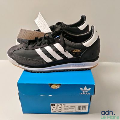 une paire de chaussures noires et blanches posée sur une boîte bleue