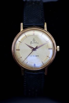 une image d'une montre-bracelet en or avec un bracelet en cuir noir