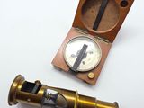 un vieux télescope en laiton dans un coffret en bois, posé sur une surface blanche