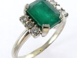 gros plan d'une bague en émeraude et diamant sur fond blanc