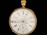 a gold pocket watch with roman numerals on the face