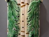 a ceramic wall sconce with green leaves on it