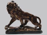 statue en bronze représentant un lion perché sur un rocher, sur fond gris