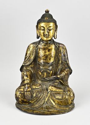 une statue en or représentant un Bouddha assis sur un socle blanc