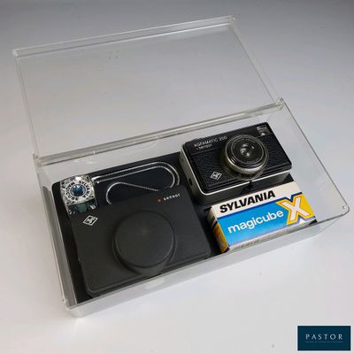 une boîte transparente contenant un appareil photo et des piles
