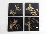 quatre sous-verres noirs et dorés ornés de fleurs et de feuilles