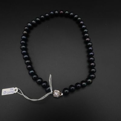 un gros plan sur un collier de perles noires muni d'un fermoir en argent