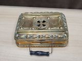 une petite boîte en métal posée sur une table, munie d'une poignée