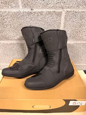 pair of black motorcycle boots sitting on a box in front of a brick wall