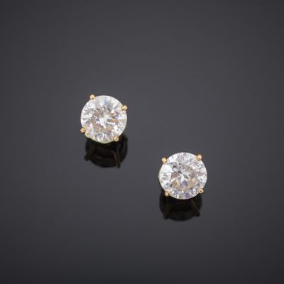 a pair of diamond earrings on a black surface