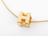 a close up of a gold necklace with a letter h on it
