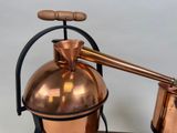 a copper pot with a wooden handle on a table