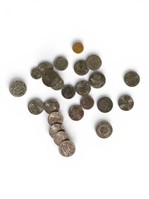 some coins are scattered on a white surface with a coin in the foreground