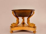 an antique brass footed bowl on a stand on a white background
