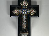 une croix accrochée au mur, avec un vase devant