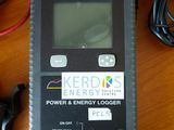 un petit appareil électronique posé sur une table à côté d'un enregistreur de consommation électrique et d'énergie