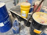 de nombreux barils de pétrole posés à même le sol, à côté d'une grille métallique