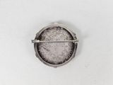 a silver brooch with a picture of a woman on it