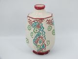 a white vase with a red handle and a pattern on it