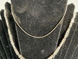 a silver necklace with a chain on it on a display