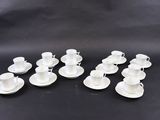 six white coffee cups and saucers on a black surface