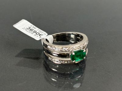 une image représentant une bague sertie d'émeraudes et de diamants sur un fond noir