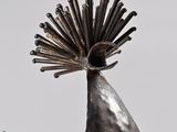 a metal sculpture of a bird with a feather on it ' s head