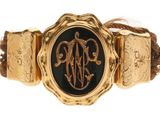 une photo d'un bracelet doré et noir orné d'un monogramme