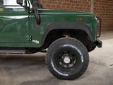 a green truck parked in a garage with a brick wall