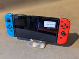une manette de jeu Nintendo Wii rouge et bleue posée sur un support