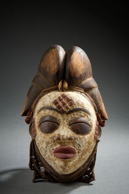 a close up of a wooden mask with a bird on top of it
