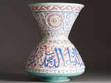 a vase with arabic writing on it sitting on a table