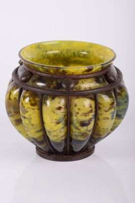 a yellow and brown vase sitting on a white surface